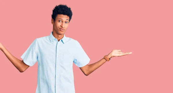 若いアフリカ系アメリカ人の男性は カジュアルな服を着て腕や手を上げて混乱した表情 疑わしい概念 — ストック写真