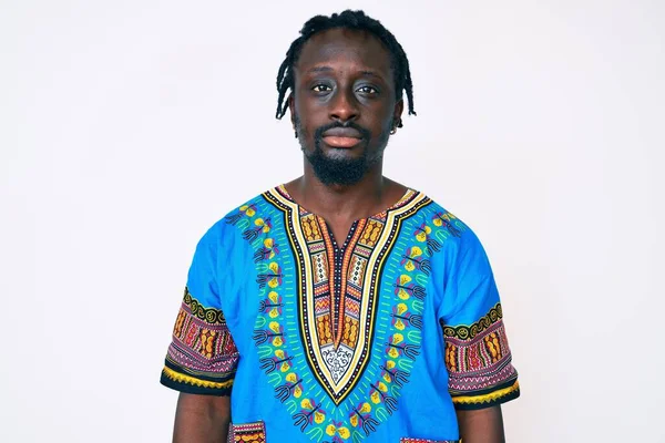 アフリカの伝統的なTシャツを着て顔に深刻な表情を持つ若いアフリカ系アメリカ人の男性 カメラを見ているだけで — ストック写真