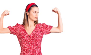 Elbise ve diyadem giyen genç ve güzel bir kız gururla gülümseyen kol kaslarını gösteriyor. fitness konsepti. 