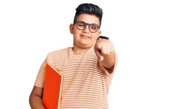 Küçük çocuk elinde gözlüklerle seni ve kamerayı işaret eden olumlu ve neşeli bir gülümsemeyle kitabı tutuyor. 