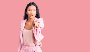 İş kıyafetleri giymiş genç ve güzel bir Latin kız kameraya kızgın ve sinirli bir şekilde seni işaret ediyor. 