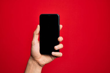 Kafkas genci elinde akıllı telefon var. İzole edilmiş kırmızı arkaplanda ekranı gösteriyor.