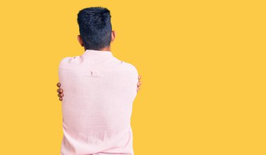 Yakışıklı Latin Amerikalı genç adam rahat bir yaz gömleği giyip kendine sarılıyor. Mutlu ve pozitif. Sevgi ve özgüven. 