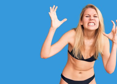 Bikini giyen genç, sarışın bir kadın öfkeden kudurmuş, elleri boğmaya çalışıyor, deli gibi bağırıyor. 