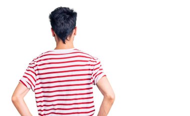 Gündelik kıyafetler giyen genç İspanyol adam kolları vücudunda geriye doğru bakıyor. 