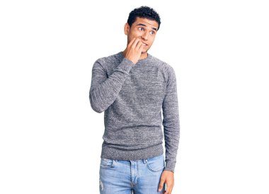 Latin asıllı yakışıklı, sıradan bir süveter giyen gergin ve gergin görünen elleri ağızdan tırnak yiyen genç bir adam. anksiyete. 