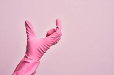 İzole edilmiş pembe arka plan üzerinde temizlik eldiveni olan beyaz bir adamın eli. Görünmez bir şeyi alıp, parmaklarında boşluk gösteren bir nesneyi tutuyor.