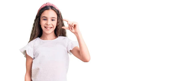 カジュアルな白いTシャツを着た可愛いヒスパニック系の女の子が笑顔で 指を見てカメラで小さなサイズの看板をして手で自信を持ってジェスチャー 概念を測定し — ストック写真