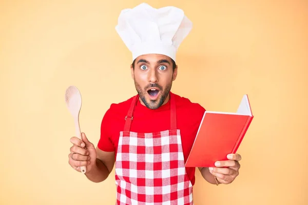 Jonge Spaanse Man Draagt Professionele Bakker Schort Lezen Kookboek Bang — Stockfoto