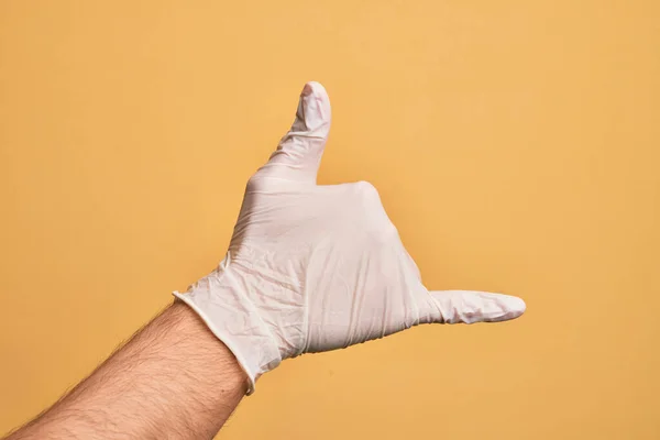 Mão Homem Jovem Caucasiano Com Luva Médica Sobre Fundo Amarelo — Fotografia de Stock