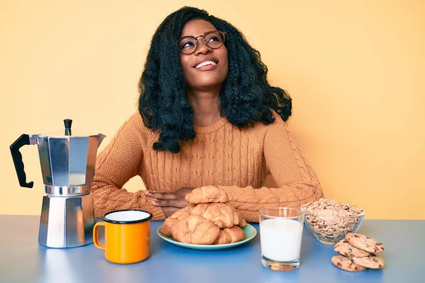 美しいアフリカの女性は テーブルの上に座っている側に見て朝の朝食を食べます 自然な顔と自信を持って笑顔でプロファイルのポーズをリラックス — ストック写真