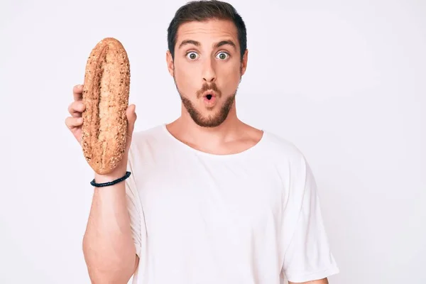 Νεαρός Όμορφος Άντρας Που Κρατάει Ψωμί Ολικής Άλεσης Φοβισμένος Και — Φωτογραφία Αρχείου
