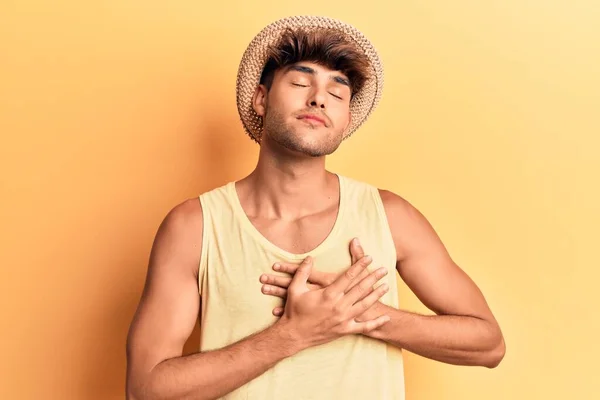 若いヒスパニック系の男の胸に手で笑みを浮かべて夏の帽子を着て 目の顔に感謝のジェスチャーで閉じます 健康の概念 — ストック写真