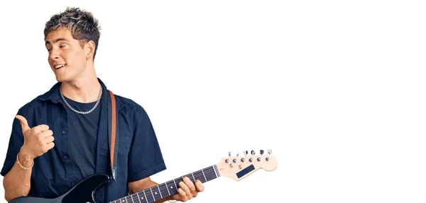 Joven Hombre Guapo Tocando Guitarra Eléctrica Apuntando Pulgar Hacia Lado —  Fotos de Stock