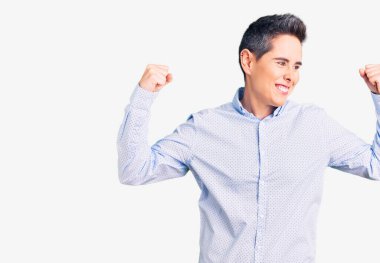 Kısa saçlı, iş kıyafetleri giyen, gururla gülümseyen kol kaslarını gösteren genç bir kadın. fitness konsepti. 