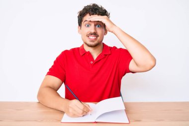 Masaya oturan kıvırcık saçlı, kafası karışık, şaşırmış ve kızgın yüzlü genç, beyaz bir adam. 