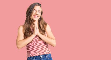 Güzel beyaz kadın, gündelik giysiler giyip ellerini birleştirip af diliyor kendinden emin bir şekilde gülümsüyor.. 