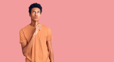 Genç, Afro-Amerikan bir adam günlük kıyafetler giyiyordu. Kuşku üzerine yoğunlaşmıştı. Parmakları çenesinde ve yukarı bakıyordu. 