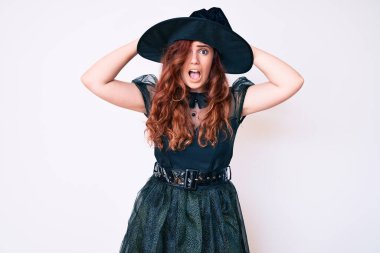 Cadılar Bayramı kostümü giyen genç ve güzel bir kadın çılgın ve elleri başının üstünde korkmuş, korkmuş ve ağzı açık şoktan şaşırmış. 