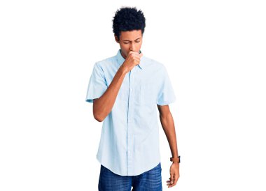 Genç Afro-Amerikalı bir adam günlük giysiler giyiyor kendini iyi hissetmiyor ve soğuk algınlığı veya bronşitin belirtisi olarak öksürüyor. sağlık hizmeti kavramı. 