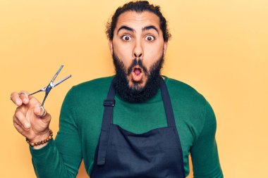 Genç Arap adam berber önlüğü takıyor. Korkmuş ve ağzı açık kalmış, şaşırmış ve şaşırmış. 