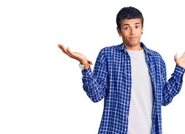 Sıradan kıyafetler giyen, kafası karışmış, elleri ve kolları havada genç bir Afrikalı Amerikalı. şüphe kavramı. 