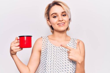 Genç ve güzel sarışın kadın kahveyi tutarken gülümsüyor. 