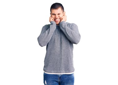 Gürültülü müziğin sesi için kulaklarını parmaklarıyla kapatan sıradan süveter giyen genç yakışıklı bir adam. sağır kavramı. 