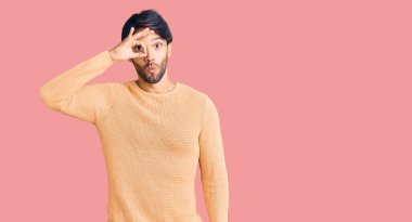 Yakışıklı İspanyol bir adam sıradan bir süveter giyiyor. Şaşırmış yüz ifadesiyle şaşırmış, parmaklarının arasından bakıyor. İnançsız ifade. 