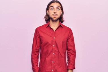 İş kıyafetleri giymiş, komik yüzlü, yanak şişiren genç yakışıklı bir adam. Havayla şişmiş ağız, çılgın bir ifade.. 