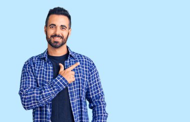 Gündelik kıyafetler giyen, neşeli, yüzünde gülümseme olan genç İspanyol adam mutlu ve doğal bir ifadeyle elini ve parmağını kaldırdı. 