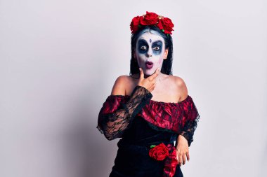 Ölü makyajlı bir Meksika günü giyen genç kadın elleri çenesinde olan inançsızlık, şaşkınlık ve şaşkınlık dolu bir ifade takınıyor. 