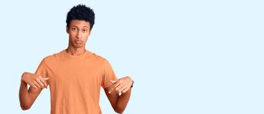 Genç Afro-Amerikan adam günlük giysiler giymiş üzgün ve üzgün görünüyor, parmaklarıyla yön gösteriyor, mutsuz ve depresif.. 