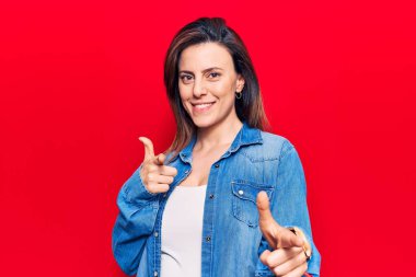 Gündelik giysiler içinde genç ve güzel bir kadın mutlu ve komik yüzüyle kamerayı işaret ediyor. iyi enerji ve titreşimler. 