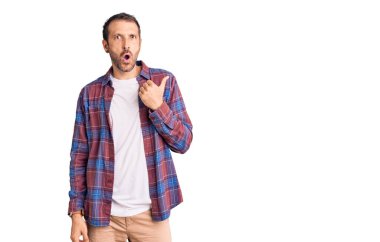 Gündelik giysiler giyen genç yakışıklı adam elleri yana doğru işaret ederek şaşırdı, ağzı açık hayret içinde kaldı.. 