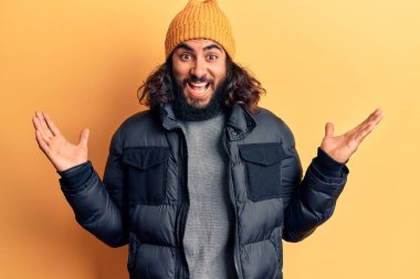 Gündelik kışlık kıyafetler giyen genç Arap adam zaferi mutlu bir gülümsemeyle ve kazanan yüz ifadesiyle kutluyor. 