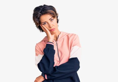 Spor giyinen genç ve güzel bir kadın kollarını kavuşturarak depresyondan yorgun ve sıkılmış göründüğünü düşünüyor.. 