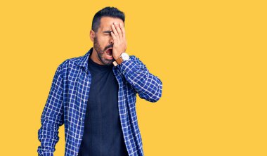 Latin asıllı genç bir adam günlük kıyafetler giyiyor. Yarı yüzünü, göz ve ağzını eliyle kapatmaktan yoruluyor. Yüzüm acıyor.. 