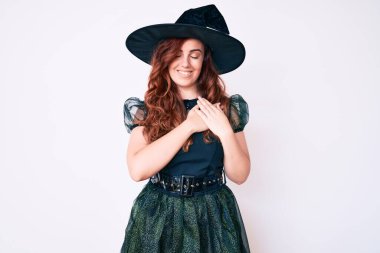 Cadı cadılar bayramı kostümü giyen genç ve güzel bir kadın. Elleri göğsünde, gözleri kapalı ve yüzünde minnet dolu bir jest ile gülümsüyor. sağlık kavramı. 