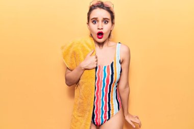 Elinde plaj havlusu tutan güzel, sarışın bir kadın. Şaşırtıcı bir şekilde ağzı açık kalmış, korkmuş ve şaşkın bir halde. 