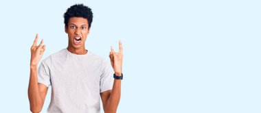 Sıradan kıyafetler giymiş, çılgın bir ifadeyle bağıran, elleri havada rock sembolü yapan genç bir Afrikalı Amerikalı. Müzik yıldızı. ağır kavram. 