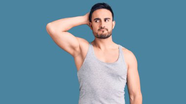 Mayolu ve kolsuz tişörtlü genç bir adam soru sorup kafasını karıştırıyor. Şüpheyle kararsız, kafa kafaya düşünerek. Düşünceli kavram. 