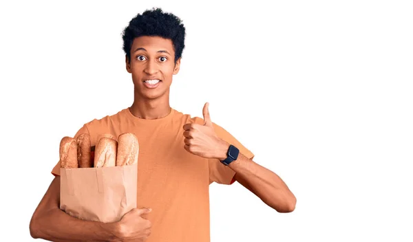 Mladý Afroameričan Drží Papírový Sáček Chlebem Dělá Šťastné Gesto Rukou — Stock fotografie