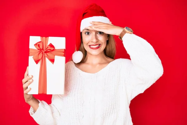 Junge Brünette Frau Trägt Weihnachtsmütze Und Hält Ein Geschenk Gestresst — Stockfoto
