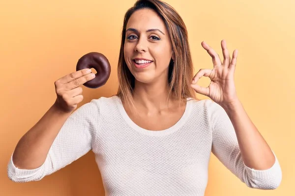 도넛을 아름다운 여자가 손가락으로 글씨를 다정하게 미소짓는 상징을 — 스톡 사진