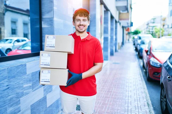 Jovem Homem Entrega Caucasiano Sorrindo Feliz Segurando Pacotes Papelão Andando — Fotografia de Stock