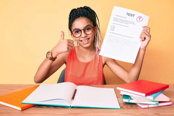 Young african american girl child with braids showing failed exam smiling happy and positive, thumb up doing excellent and approval sign