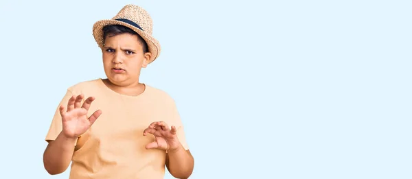 夏の帽子をかぶっている小さな男の子とハワイの水着は嫌悪反応のために嫌悪感の表情 不満と恐ろしい嫌な顔をしてうんざりしている 手を挙げて — ストック写真