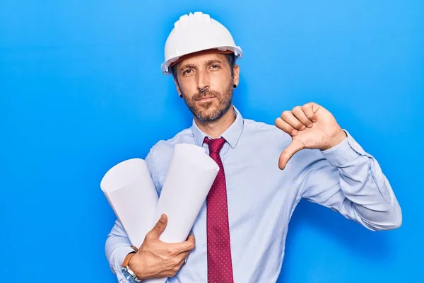 Joven Hombre Guapo Usando Arquitecto Hardhat Sosteniendo Planos Con Cara —  Fotos de Stock