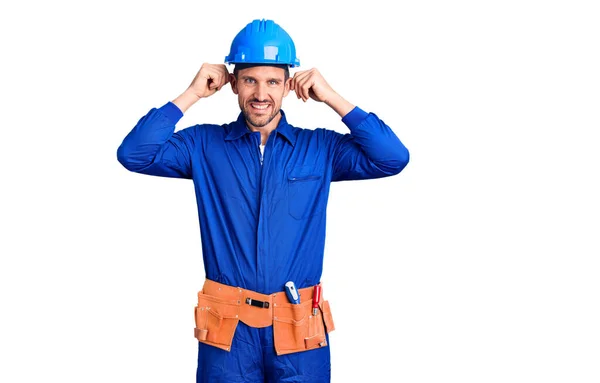 Homem Bonito Jovem Vestindo Uniforme Trabalhador Hardhat Sorrindo Puxando Orelhas — Fotografia de Stock